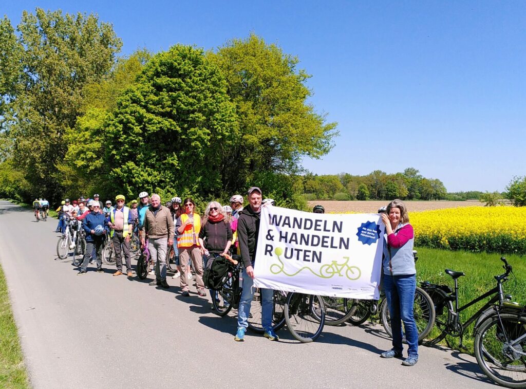 Gruppe mit Plakat in Hand vor Rapsfeld