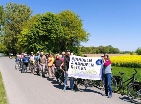 Gruppe mit Plakat in Hand vor Rapsfeld